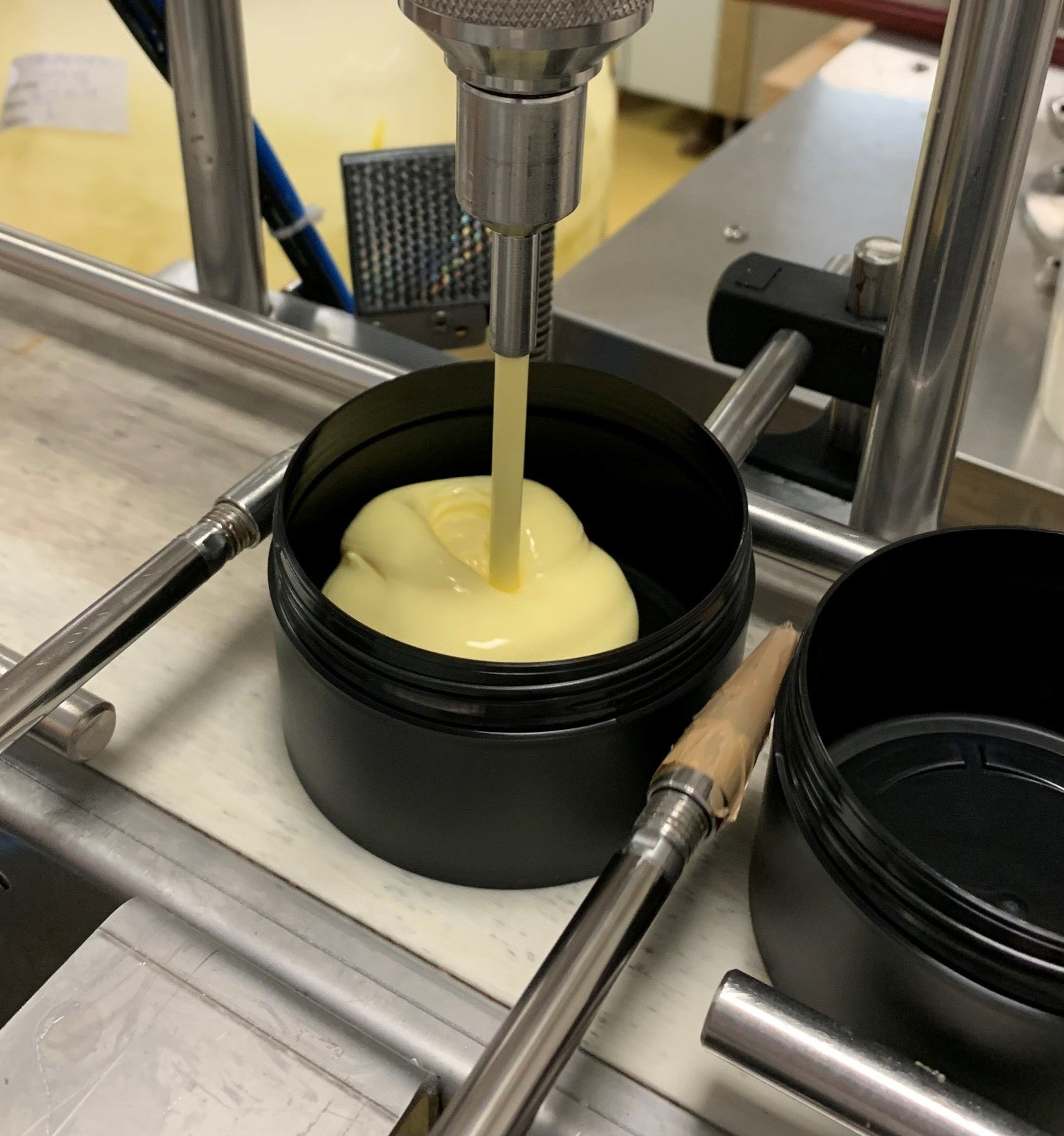 egy gép krémet tölt a tégelyébe